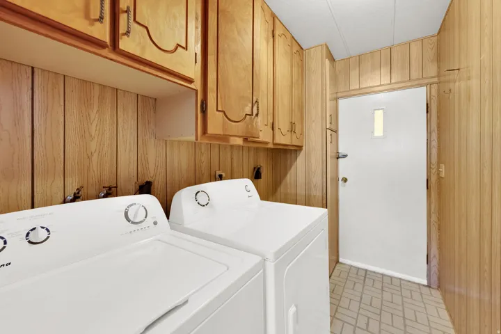 Dedicated laundry area featuring wood paneling, wood cabinetry, and a patterned floor