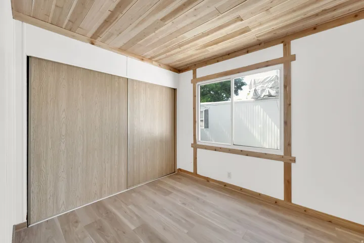 Interior space featuring wood-finish flooring, a coordinating wood-paneled ceiling, and a prominent sliding closet with light wood-finish doors