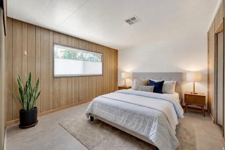 Master Bedroom featuring a light-colored accent wall, wood-paneled walls, and a window with blinds