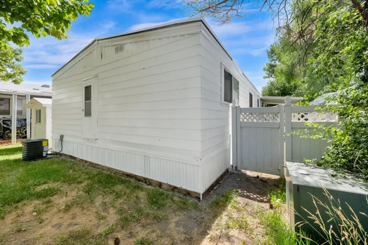 White siding exterior with a white lattice-top privacy fence and gate