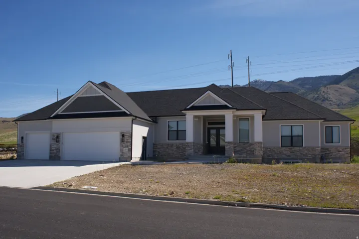 Contemporary ranch-style residence featuring a stone and siding exterior, a prominent covered entry with double front doors, a three-car garage, and a dark shingle roof