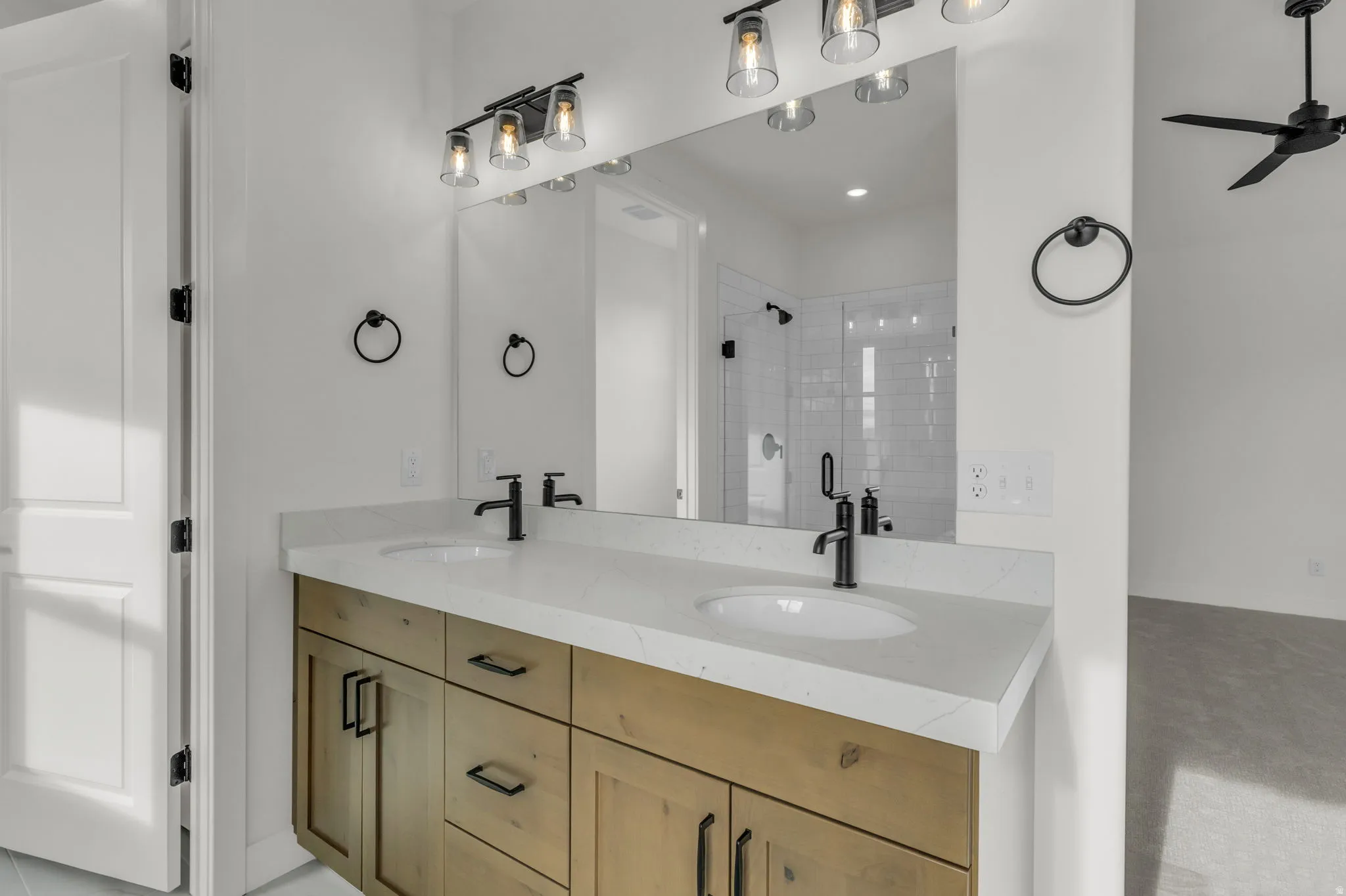 Primary bath with double sinks, stained wood cabinets and quartz slab countertops.