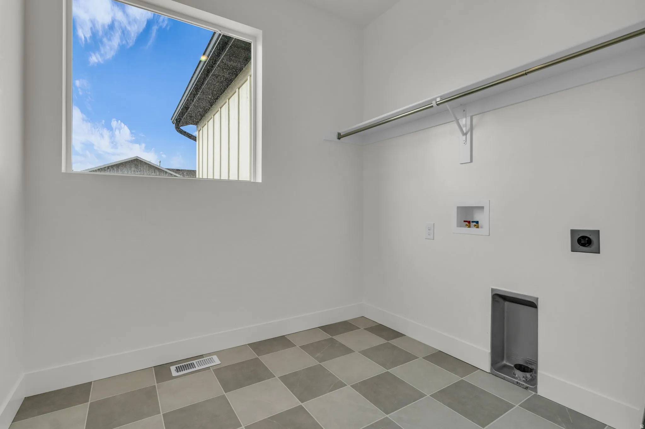 Full-size laundry room with natural light, tiled floor and washer/dryer hookups.