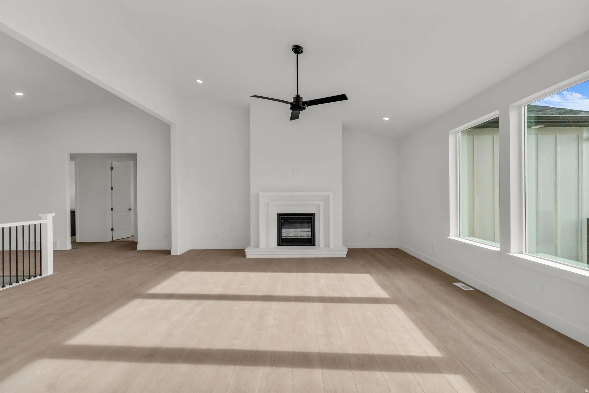 Great room with fireplace, vaulted ceiling, picture windows and ceiling fan.