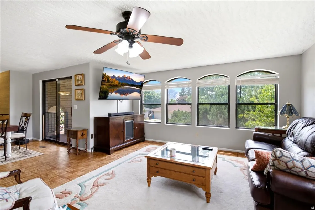 Living area featuring wood-finish flooring, a ceiling fan with integrated lighting, and a sliding glass door