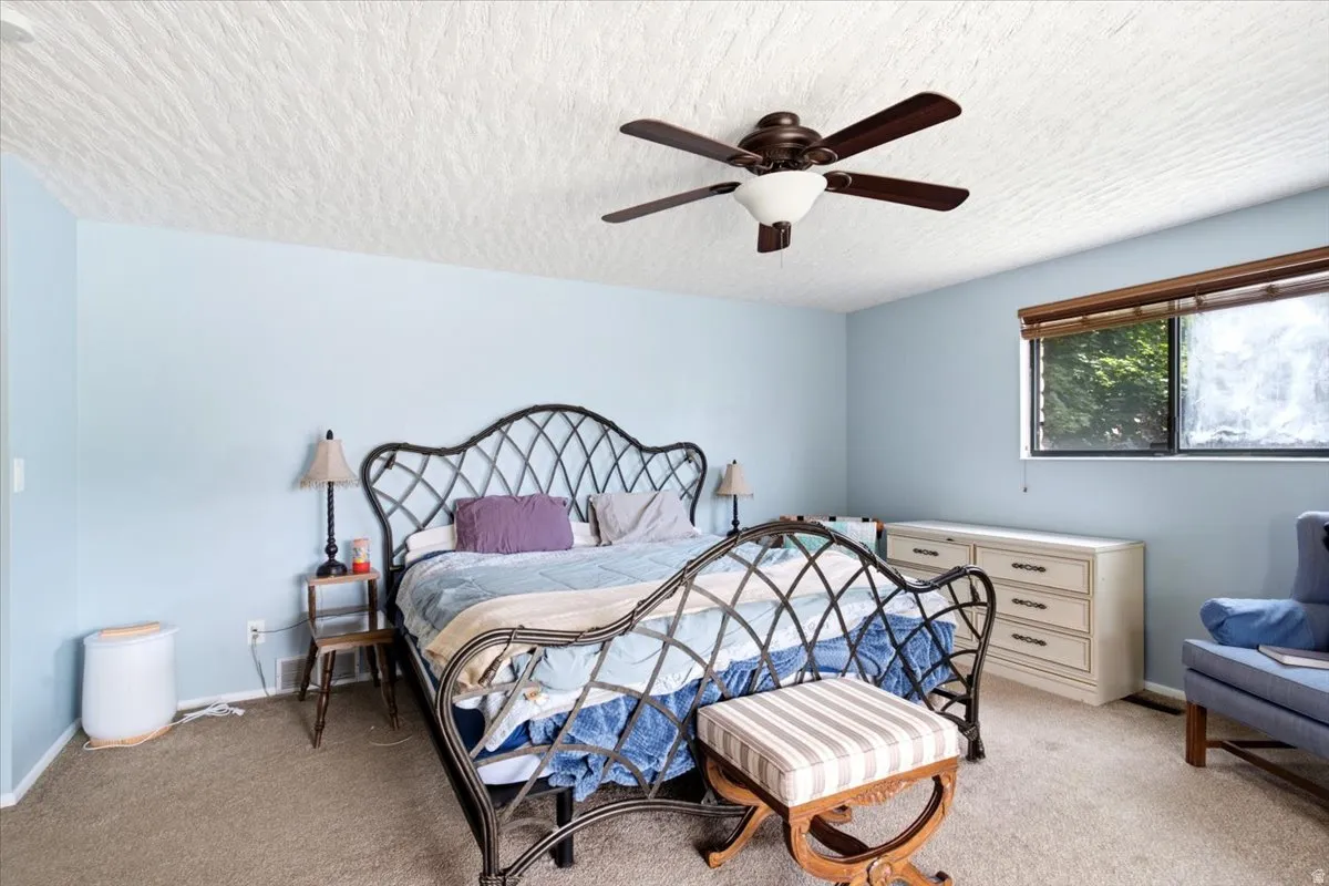 Light blue walls complement the textured ceiling in this room, featuring a dark-toned ceiling fan with integrated lighting