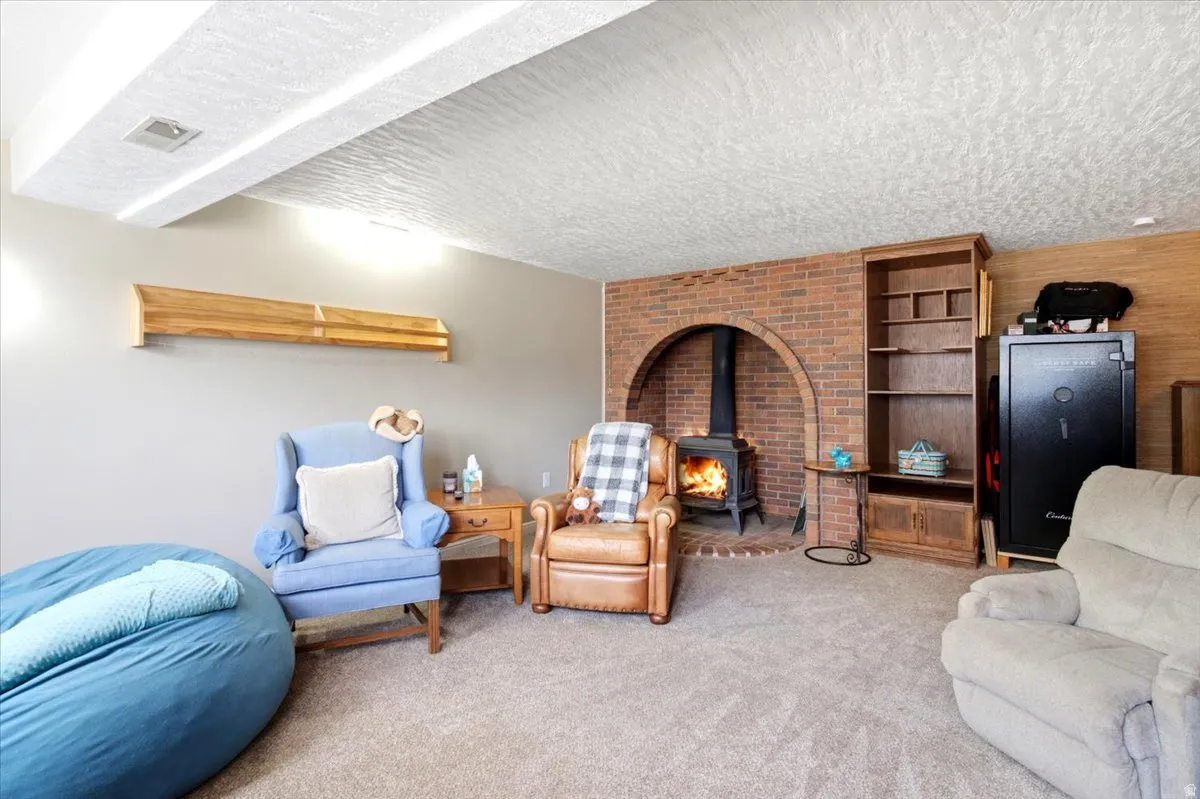 Living space featuring a brick arched fireplace with a wood-burning stove, wall-to-wall carpeting, and wood-paneled accents