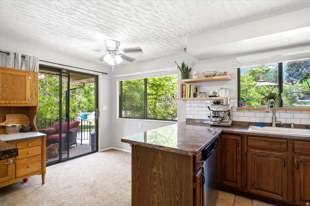 Kitchen featuring wood cabinetry, a built-in dishwasher, an integrated sink, a subway tile backsplash, and a ceiling fan
