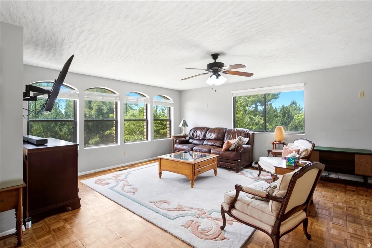 Bright living area featuring parquet wood flooring and multiple windows
