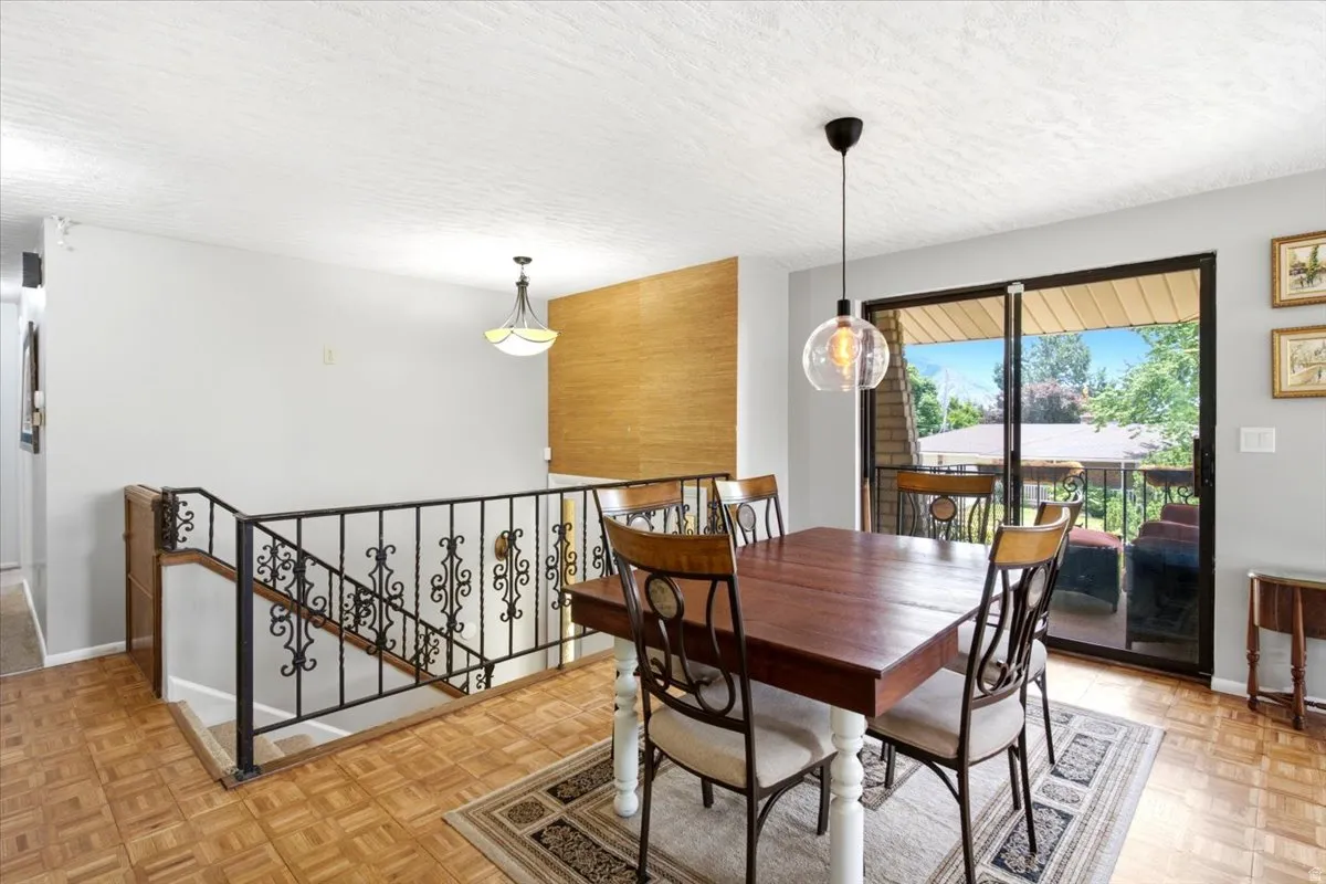 Dining area featuring wood-finish flooring, a contemporary pendant light fixture, and a textured accent wall