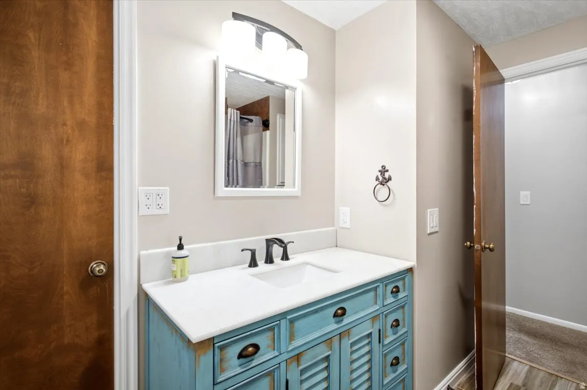 Bathroom vanity with a white countertop and integrated sink, a distressed blue cabinet base, and matte black fixtures