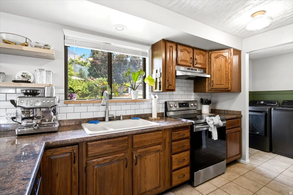 Kitchen featuring wood cabinetry, stainless steel appliances, a white subway tile backsplash, and granite countertops