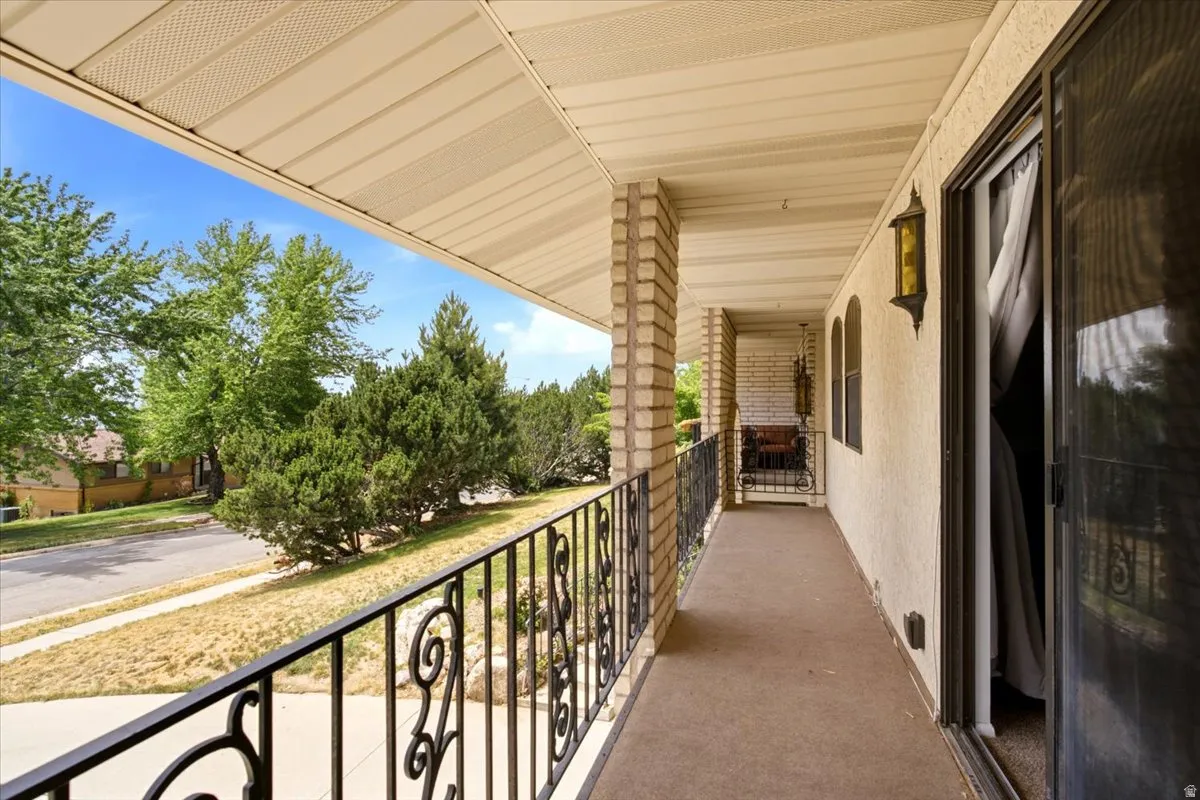 Covered balcony featuring a textured ceiling and brick columns