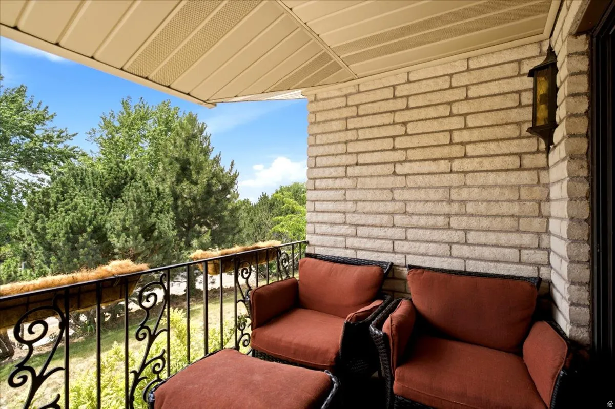 Outdoor balcony featuring a decorative wrought iron railing, light-colored brick wall, and a textured overhead soffit