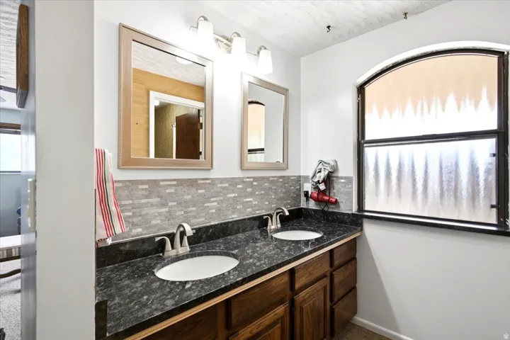 Double vanity featuring two undermount sinks set into a dark stone countertop