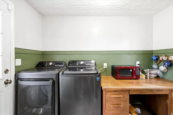 Dedicated laundry area featuring a white door with bronze hardware, two electrical outlets, and a wood-finish desk with drawers