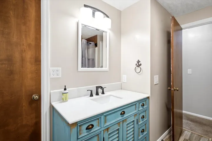Bathroom vanity with a white countertop and integrated sink, a distressed blue cabinet base, and matte black fixtures