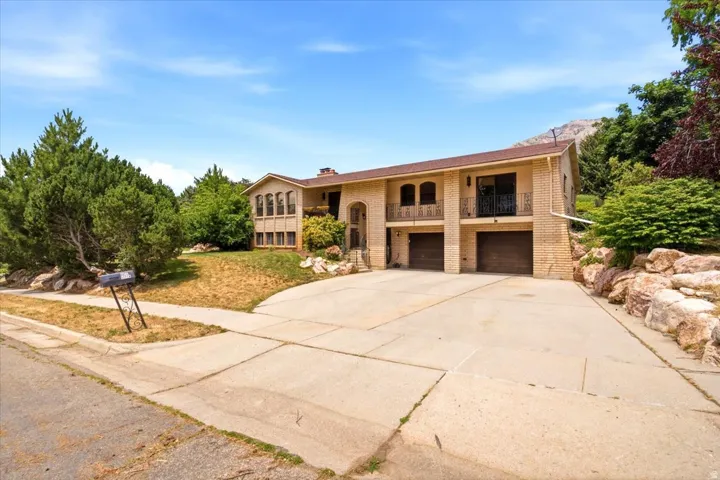 Two-story residence featuring a brick facade with a prominent two-car garage and a large concrete driveway