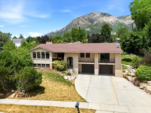 Stone-clad residence featuring a two-car garage with individual doors, a paved driveway, and multiple arch-top windows
