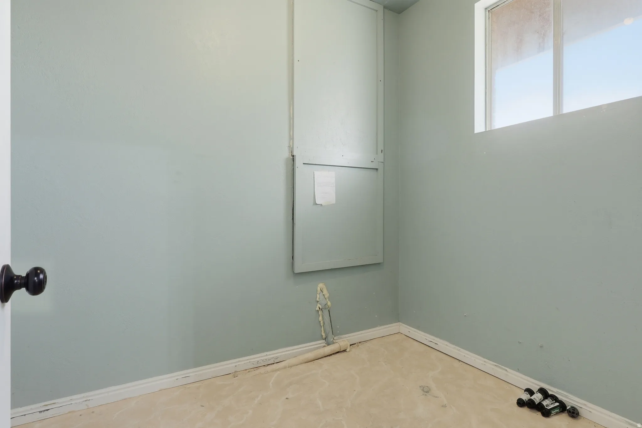 Utility space featuring a window, wall paneling, and light-colored flooring