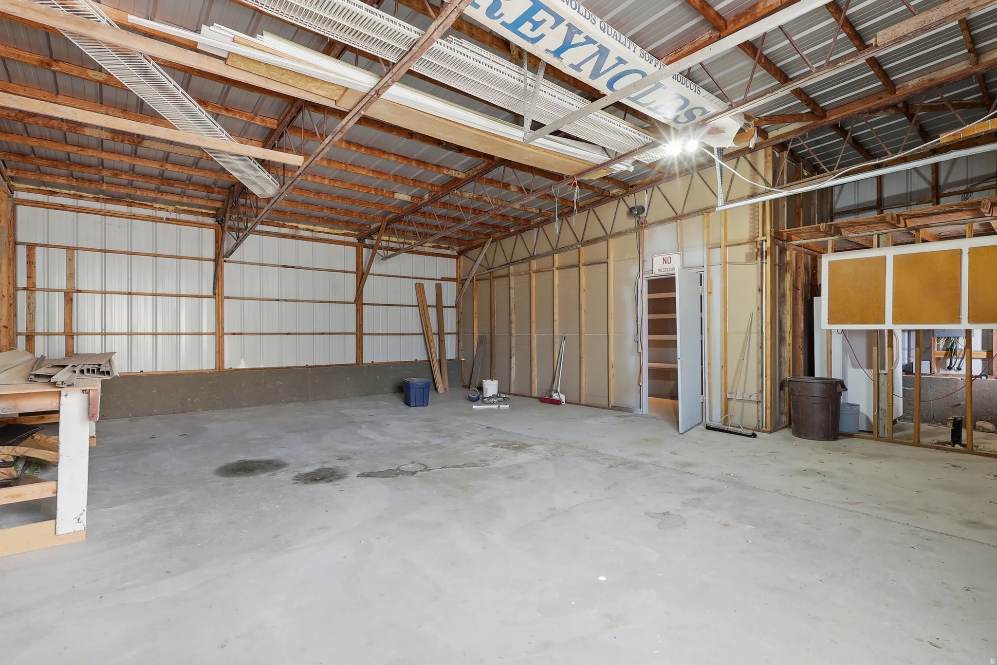 Spacious interior with exposed wood beam ceiling, concrete flooring, and metal wall panels
