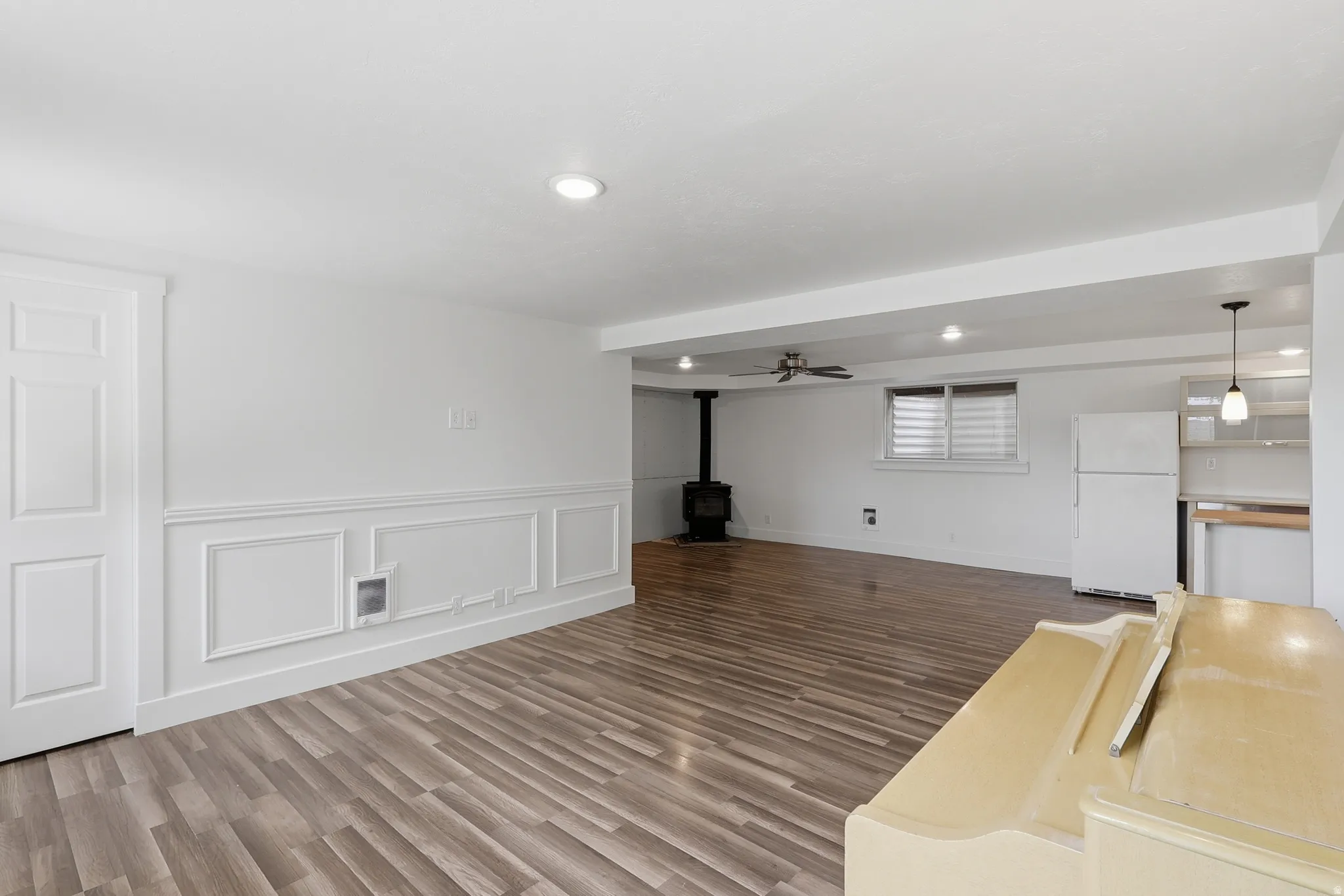Open-concept lower level featuring wood-finish flooring, recessed lighting, and a wood-burning stove
