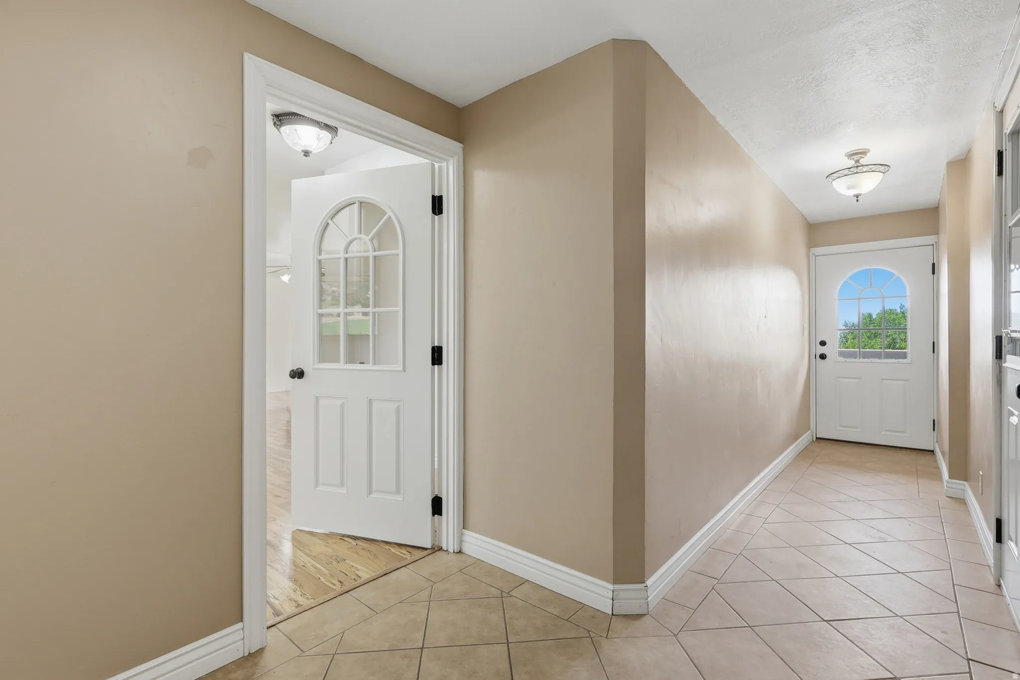 Entryway featuring light-toned tile flooring, neutral wall paint, and white trim