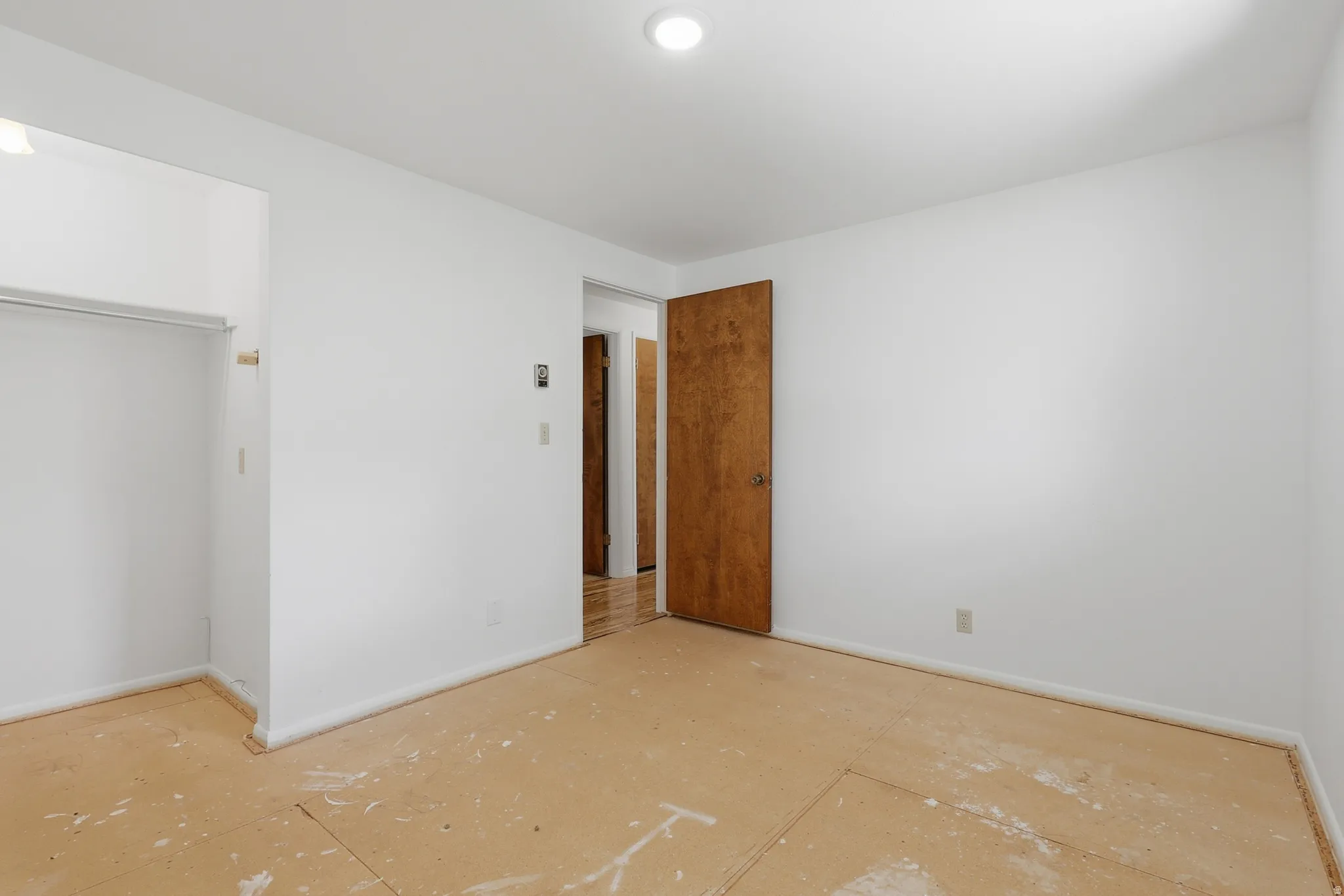 Open room featuring an unadorned closet space, a solid wood door, and baseboard trim