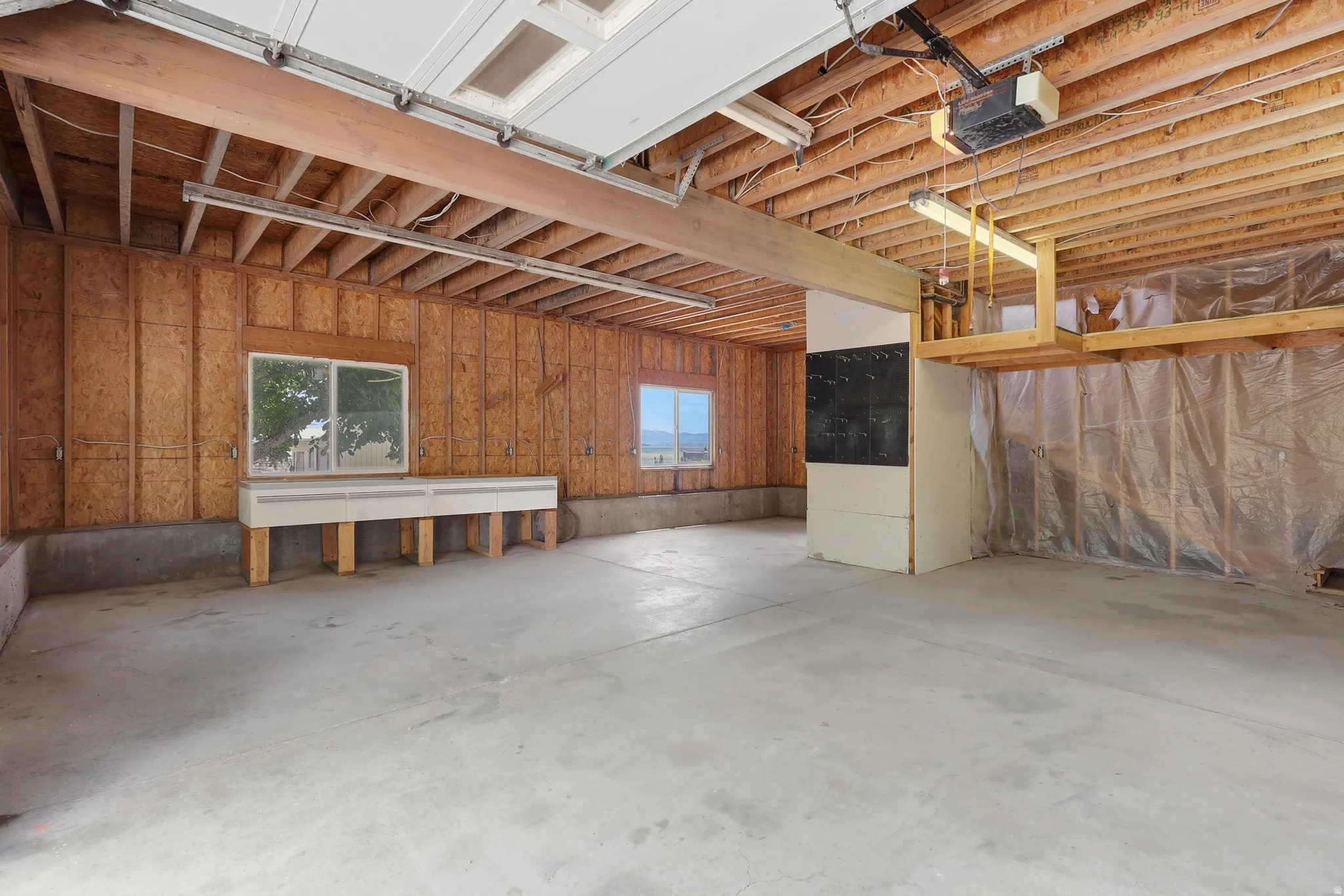 Spacious garage interior featuring a concrete floor and exposed wood ceiling joists