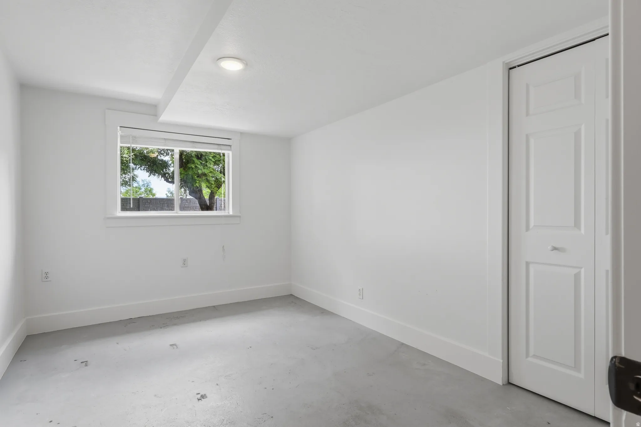 Room featuring a window with natural light, a recessed ceiling light, and a white bi-fold closet door