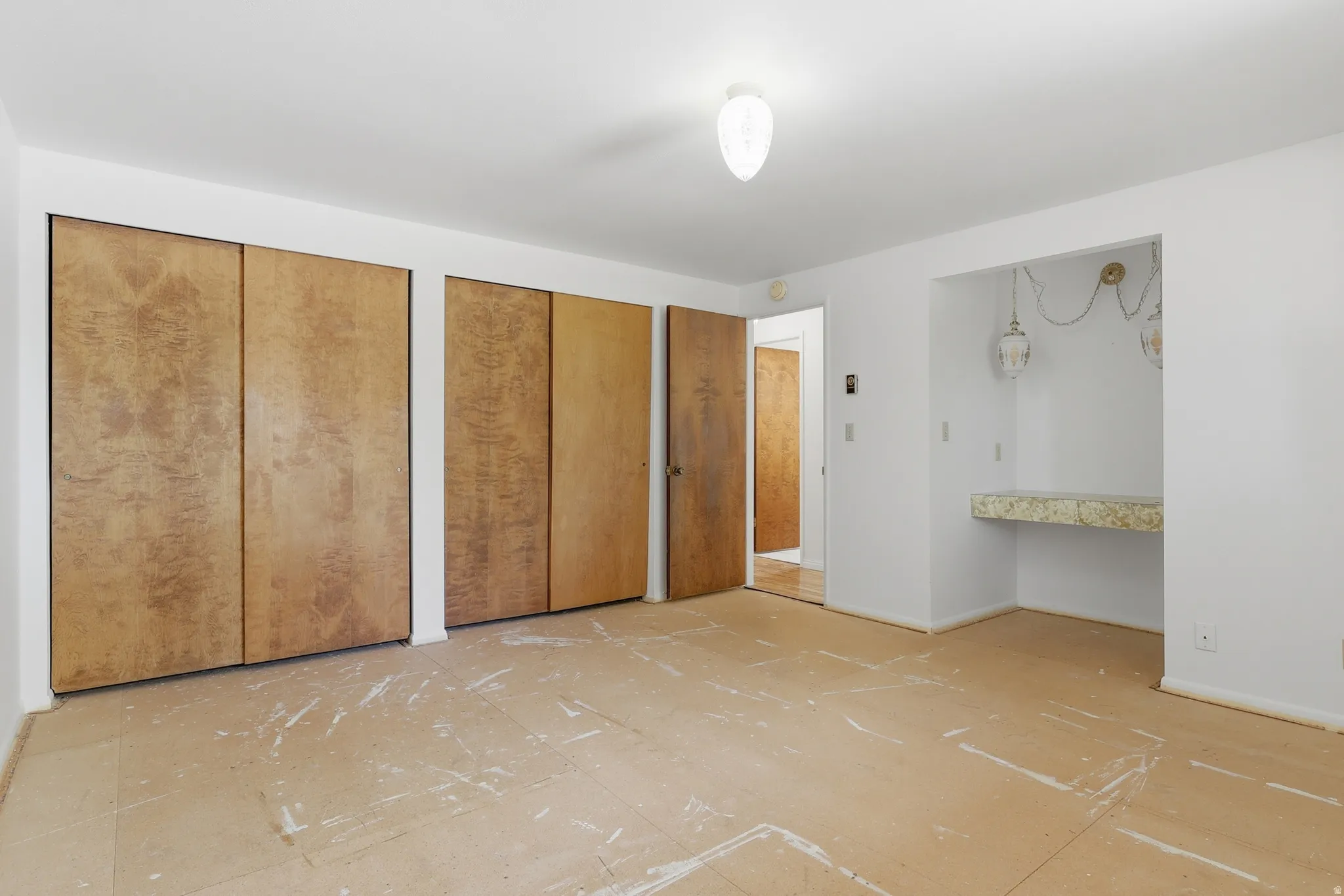 Interior room featuring natural wood-finish bi-fold closet doors, a built-in vanity niche with a patterned countertop, and a flush-mount ceiling light fixture