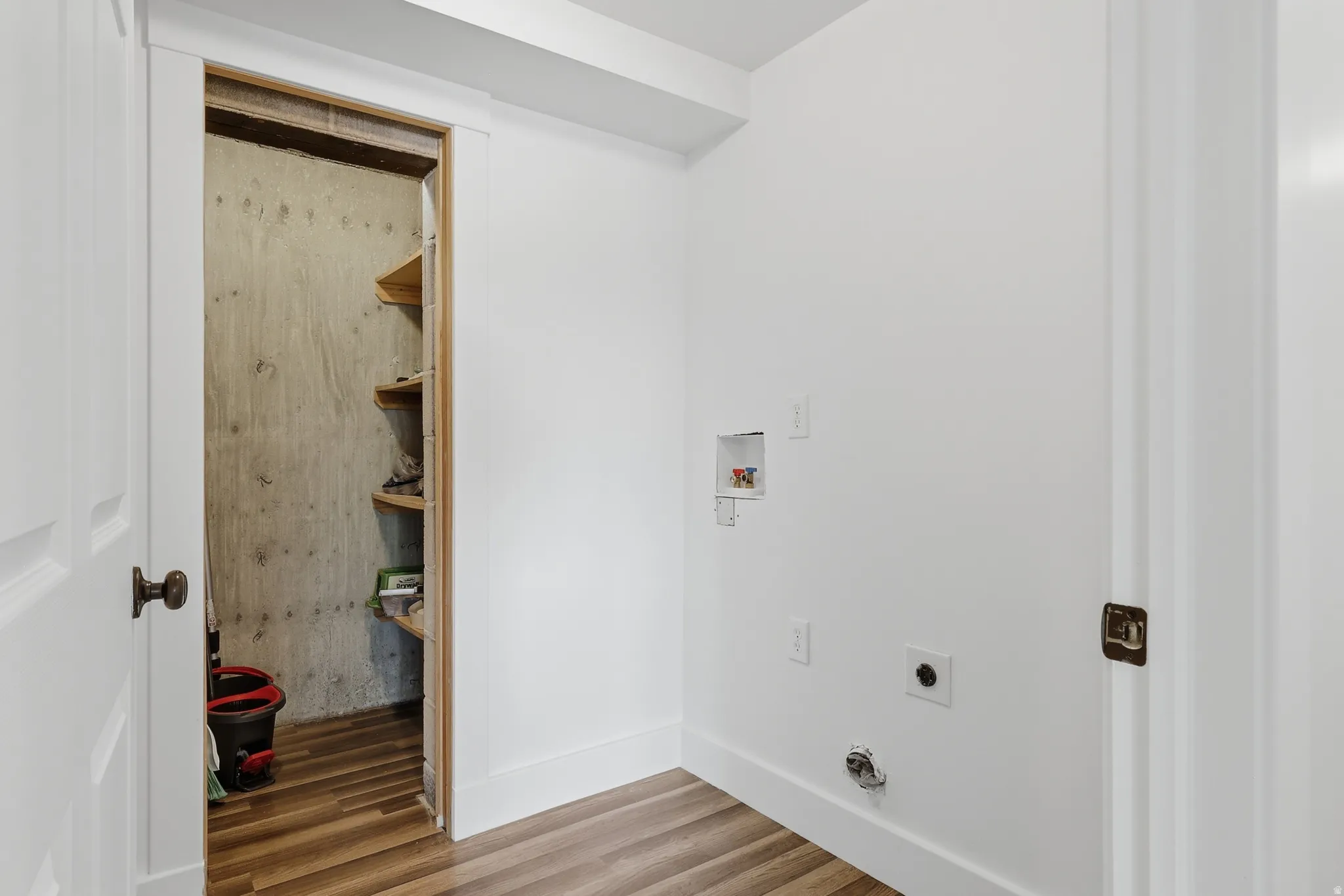 Bright utility space featuring wood-finish flooring, white walls, and a dedicated laundry appliance hookup