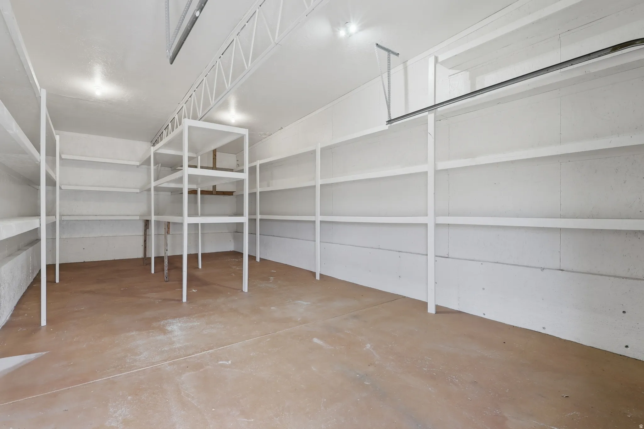 Spacious garage featuring extensive built-in shelving, concrete flooring, and ceiling-mounted lighting