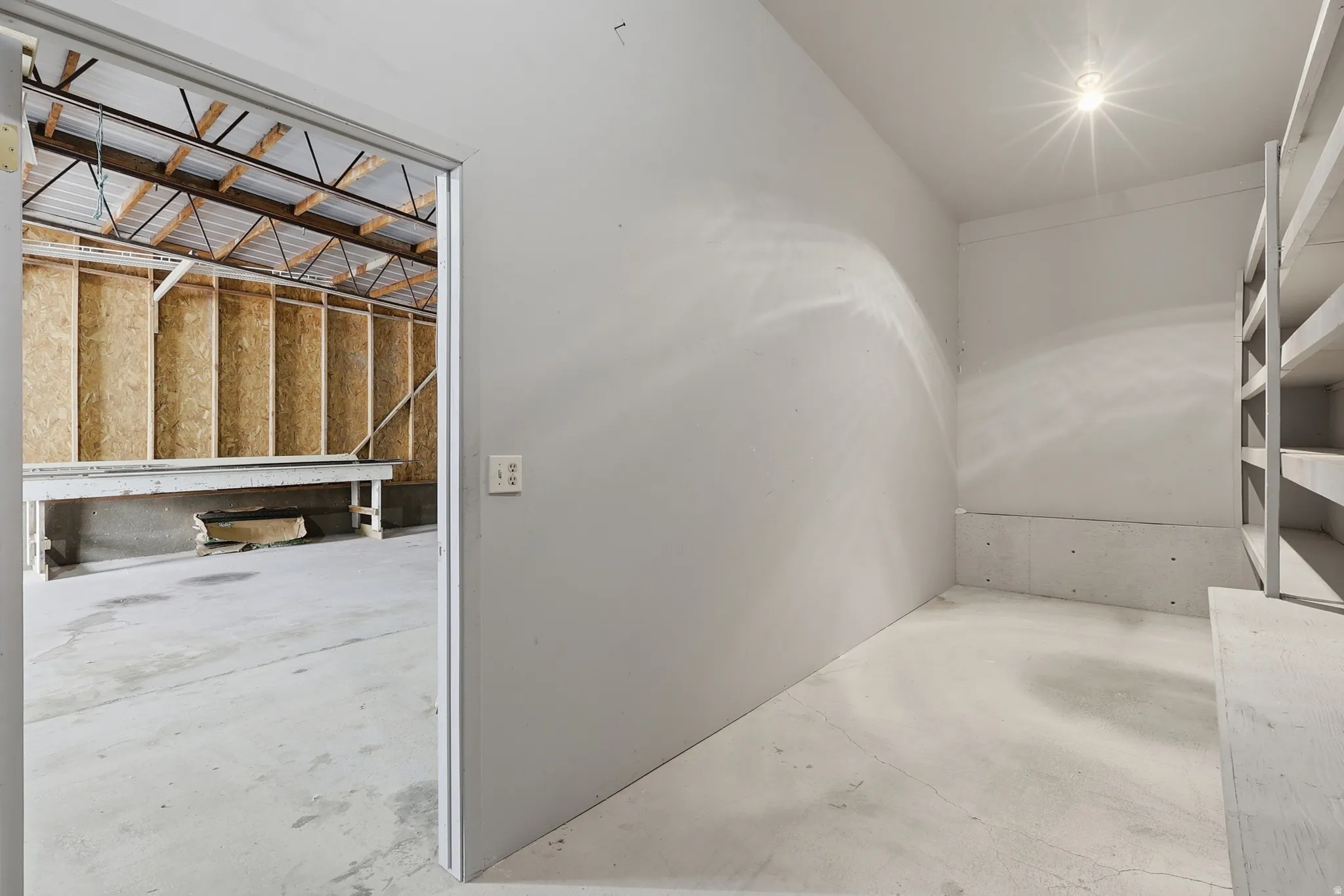Concrete flooring with built-in shelving, painted walls, and a recessed ceiling light