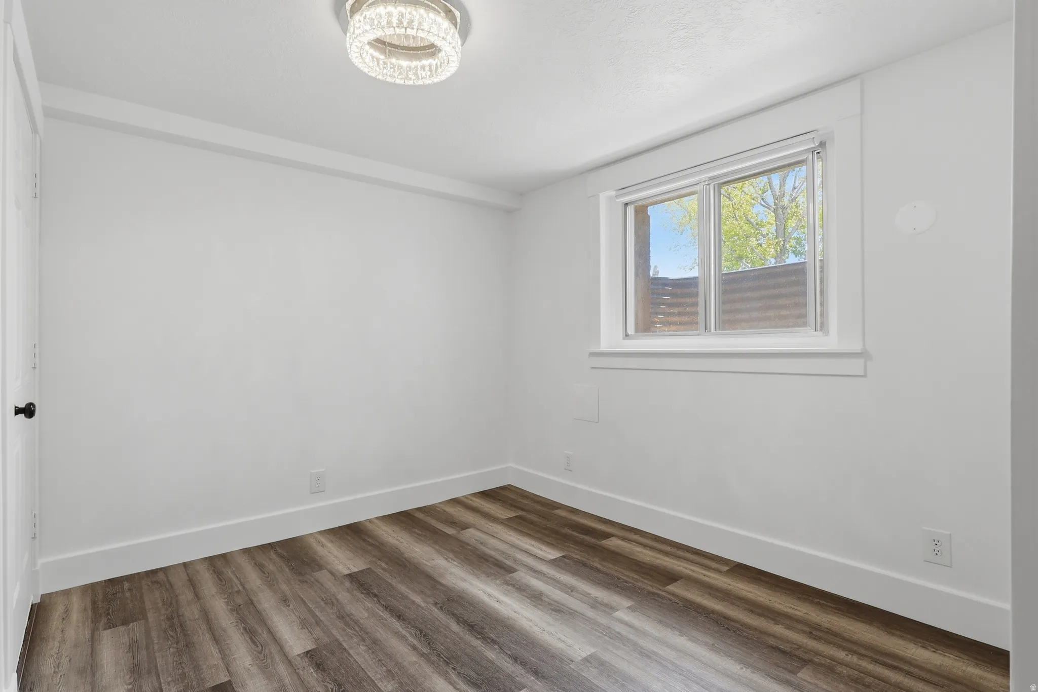 Bright room featuring wood-finish flooring, white baseboards, and a contemporary ceiling light fixture
