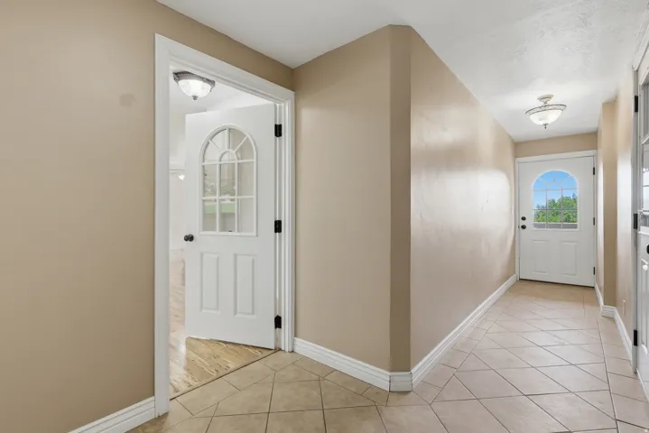 Entryway featuring light-toned tile flooring, neutral wall paint, and white trim