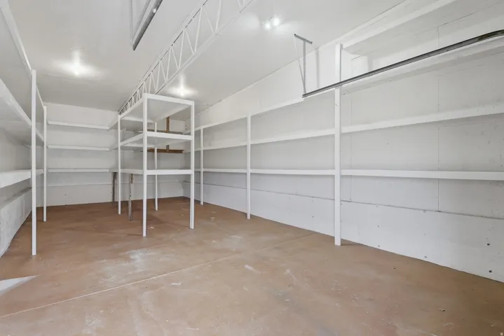 Spacious garage featuring extensive built-in shelving, concrete flooring, and ceiling-mounted lighting