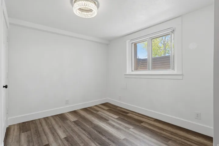 Bright room featuring wood-finish flooring, white baseboards, and a contemporary ceiling light fixture