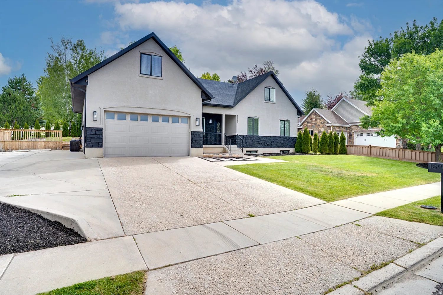 Contemporary stucco and stone-clad residence featuring a two-car garage with transom windows