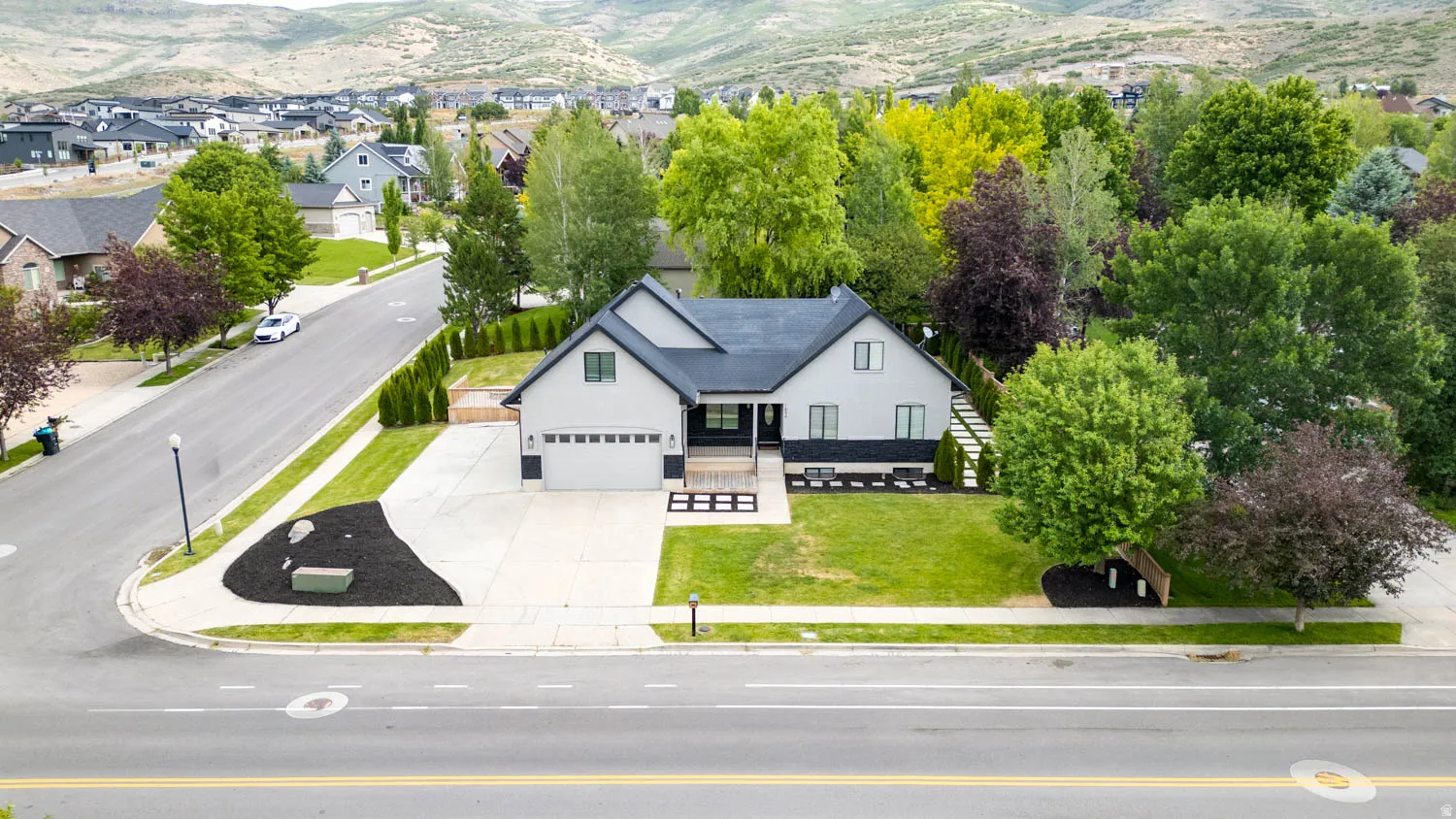 Contemporary residence featuring a two-car garage, dark-toned roof, and a light-colored exterior finish
