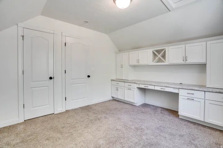 Built-in desk area featuring extensive white cabinetry, a built-in wine rack, and a light-toned countertop
