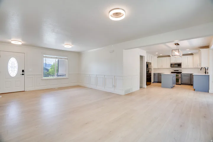 Open-concept living space featuring wood-finish flooring, wainscoting, and recessed lighting