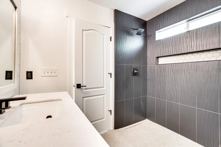 Contemporary bathroom featuring a walk-in shower with textured dark gray tile walls, a horizontal mosaic tile niche, and a contrasting light-colored hex tile shower floor