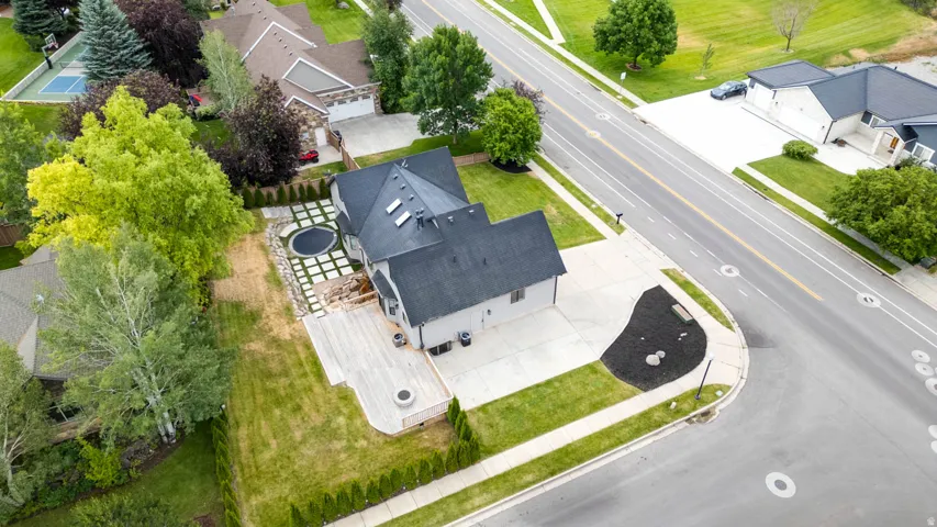 Expansive outdoor living space featuring a large wooden deck, built-in fire pit, and a paver patio with a circular inset