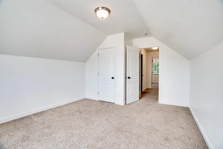 Carpeted room featuring sloped ceilings, white walls, and a semi-flush mount ceiling light