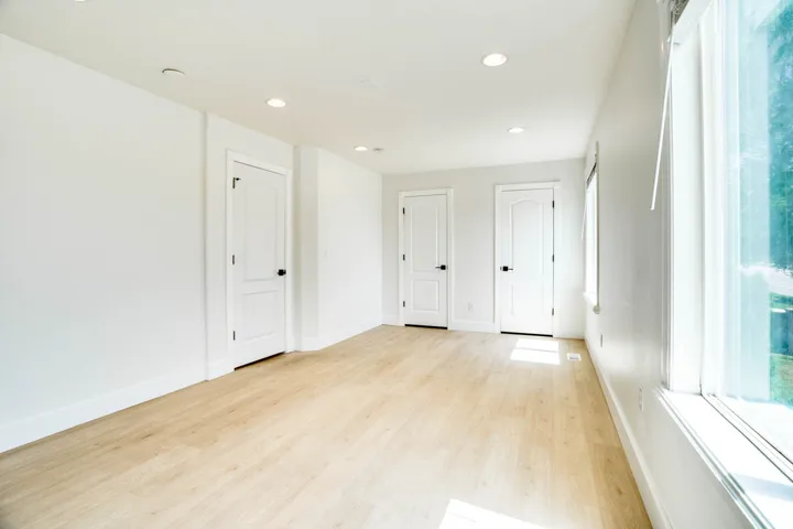 Bright room featuring light wood-finish flooring, white walls, multiple windows, and recessed lighting
