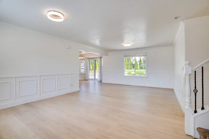 Spacious room featuring light wood-finish flooring, wainscoting, and crown molding