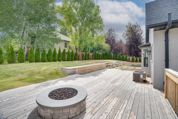 Expansive wood deck featuring a built-in fire pit with stone surround and a raised wood planter box