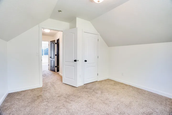 Carpeted room featuring white walls and sloped ceilings