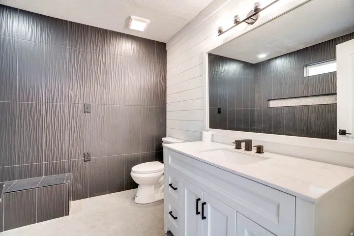 Bathroom featuring a white vanity with a light-toned countertop, a black faucet, and a large mirror